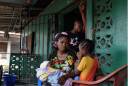 In this picture taken Sunday, Sept. 28, 2014, Finda Saah, 28, holds six-week-old Prosper Junior, as 5 year old Alice and 13-year old son Augustin look on, at their St Paul Bridge home in Monrovia, Liberia. Finda lost her husband to the deadly Ebola virus and gave birth three days later. Ebola has killed more than 1800 people in Liberia this year. As the death toll from Ebola soars, crowded clinics are turning over beds as quickly as patients are dying. This leaves social workers and psychologists struggling to keep pace and notify families, who must wait outside for fear of contagion. Also, under a government decree, all Ebola victims must be cremated, leaving families in unbearable pain with no chance for goodbye, no body to bury. (AP Photo/Jerome Delay)