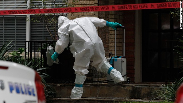 A man dressed in protective clothing treats the front porch of a Dallas apartment where one of the infected nurses resides on Sunday, October 12.