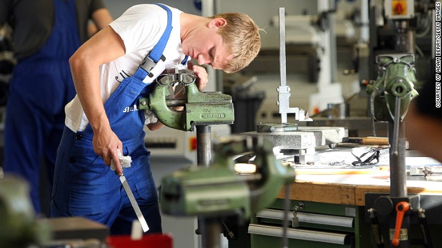 The country's unique apprenticeship scheme has played a key role in nurturing Germany's manufacturing success, with school leavers spending around 2-3 years training with companies. A trainee, pictured, files a piece of metal at a Siemens training center in Berlin. 