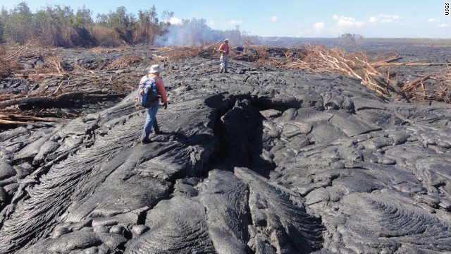 Hawaiian Volcano Observatory geologists walk over the surface of the flow to track surface breakouts along a portion of the flow margin, about a kilometer (0.6 miles) up the slope from the flow front, on October 24.
