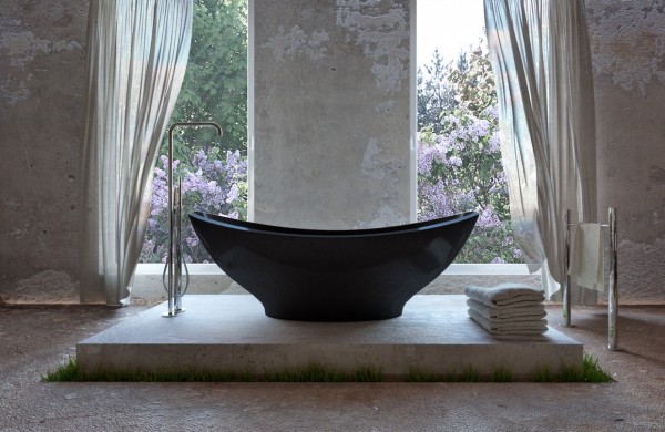 In the bathroom, a deep black tub sits elevated on its own concrete slab that is surrounded by grass. It quickly becomes like bathing in the outdoors, surrounded by blossoming flowers, which is the height of decadence.