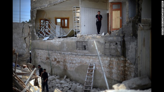 Men inspect damage at a house destroyed in an airstrike in Aleppo on April 15.