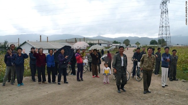 Peasants and villagers standing by the road to look at the Western cyclists