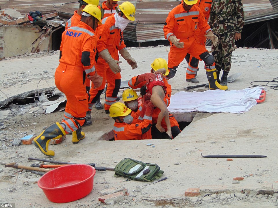 A photograph provided by India's National Disaster Response Force (NDRF) shows a young child being pulled from a hole in the ground