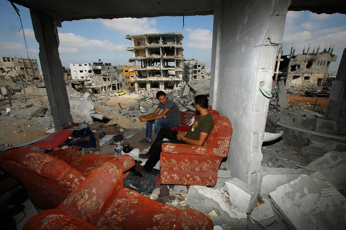 Palestinians sit amidst the rubble of their house, which witnesses said was destroyed in an Israeli offensive, in the east of Gaza City
