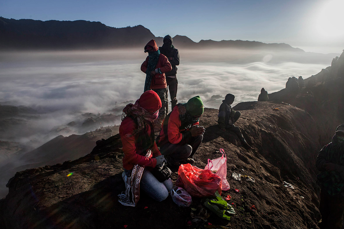 Clouds blanket the valley below as Tenggerese worshippers pray to their ancestors at the crater of Mount Bromo