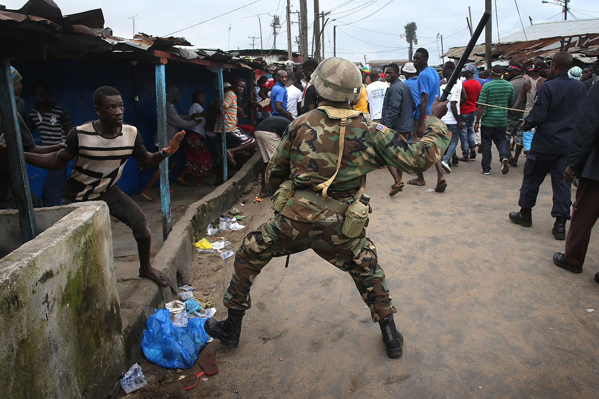 A Liberian Army soldier, part of the Ebola Task Force, beats a local resident while enforcing a quarantine on the West Point slum. The government ordered the quarantine of West Point, a congested seaside slum of 75,000, in an effort to stop the spread of the virus in the capital