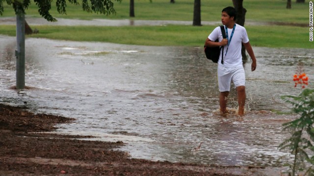 A student tries to walk along a flooded sidewalk so he can be picked up by his parents September 8 in Phoenix.