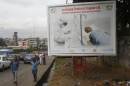 People walk past a billboard displaying a government message about Ebola on a street in Abidjan