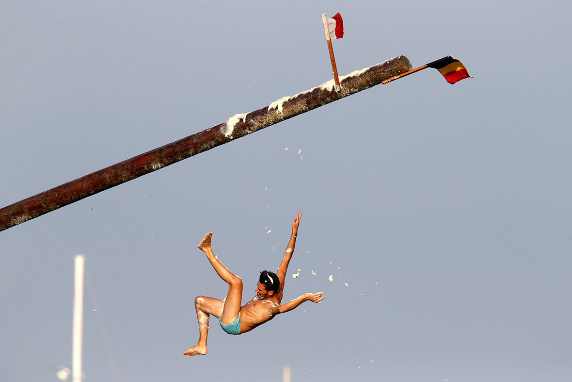 A man falls off a pole covered in grease during celebrations for the feast of St Julian near Valletta, Malta