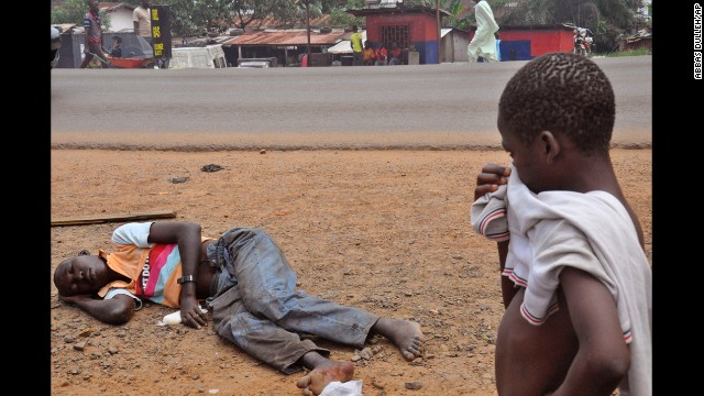 A child stops on a Monrovia street Friday, September 12, to look at a man who is suspected of suffering from Ebola.