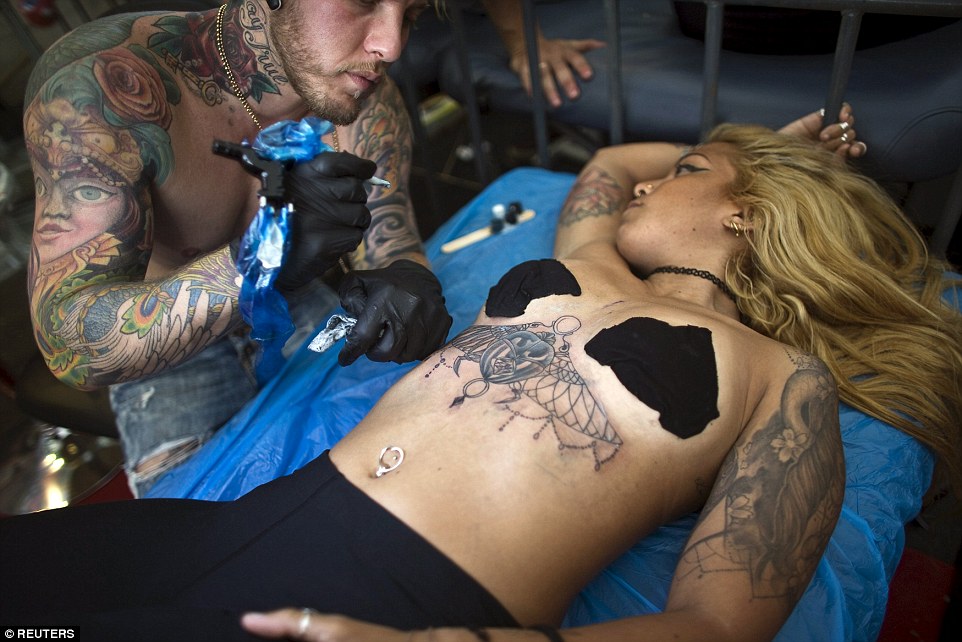 Getting intimate: A woman almost bares all while having her chest tattooed at the second body art convention in Israel yesterday