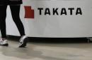 Visitor walks past displays of Takata Corp at a showroom for vehicles in Tokyo