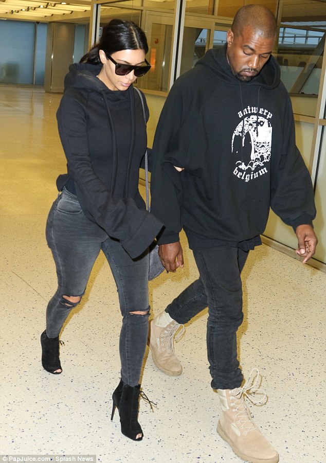 The couple that dresses together: It appears as if Kim Kardashian has been raiding her husband Kanye West's closet as the couple opted for matching outfits as they flew into New York on Tuesday
