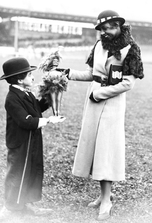 A Charlie Chaplin imitator offers a Josephine Baker doll to the...