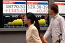 Des passants regardent un tableau d'indices boursiers, le 9 septembre 2015 à Tokyo