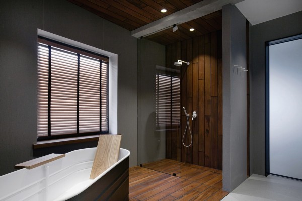 The bathroom is spacious with its own design aesthetic. The dark wood paneling on the floor extends up the wall in the shower area, giving it a natural, enveloping feel. The large soaking tub is a reclaimed washtub, which is equal parts kitschy and historic.