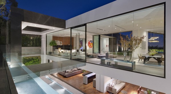 The entrance to the home takes guests over a modern answer to a medieval moat. A sleek brushed metal bridge gives a view straight through the home's glass walls from front to back, including peeks at the sleek and modern furnishings.