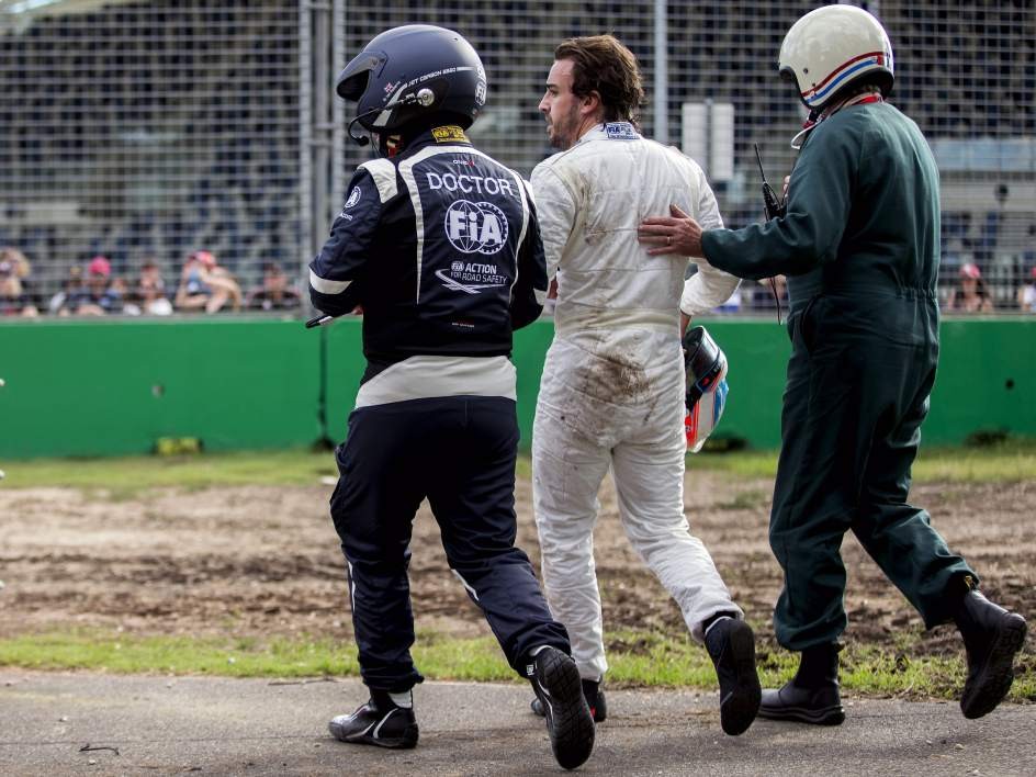 Fernando Alonso, acompañado por el médico de la FIA tras el accidente de Australia. EFE