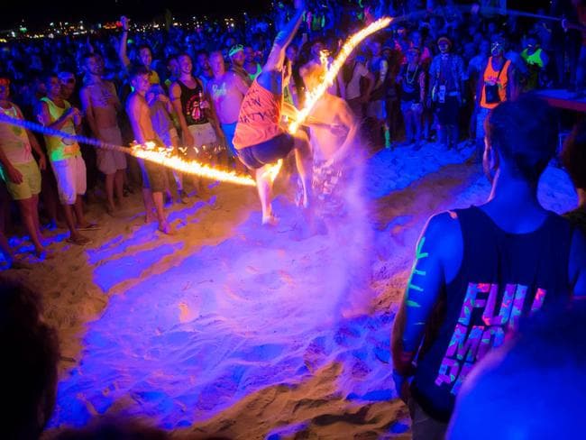 Party goers take it in turns to jump the rope of fire. Many get tangled and burnt. Picture: Tommo Williams