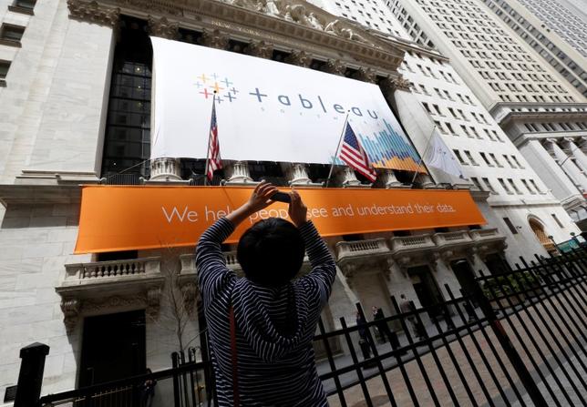 A woman takes pictures of the New York Stock Exchange, which has a Tableau Software banner on its facade, May 17, 2013. REUTERS/Brendan McDermid