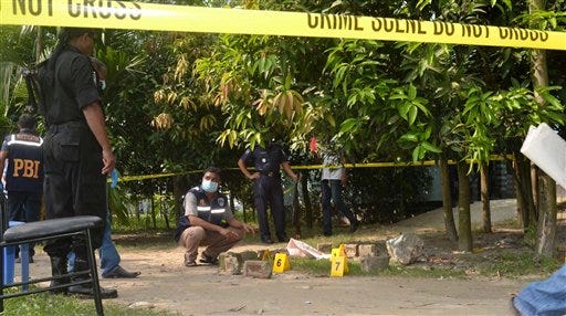 Bangladeshi security officers examine the site where a Japanese Kunio Hoshi was killed at Mahiganj village in Rangpur district, 300 kilometers (185 miles) north of Dhaka, Bangladesh, Saturday, Oct. 3, 2015. Masked assailants riding a motorbike shot and killed the Japanese man in northern Bangladesh on Saturday, police said, the second foreigner in a week to be gunned down in the South Asian country. Hoshi had started a farm in Rangpur, about 300 kilometers (185 miles) north of Dhaka, to produce grass. (AP Photo/Ripon Islam)