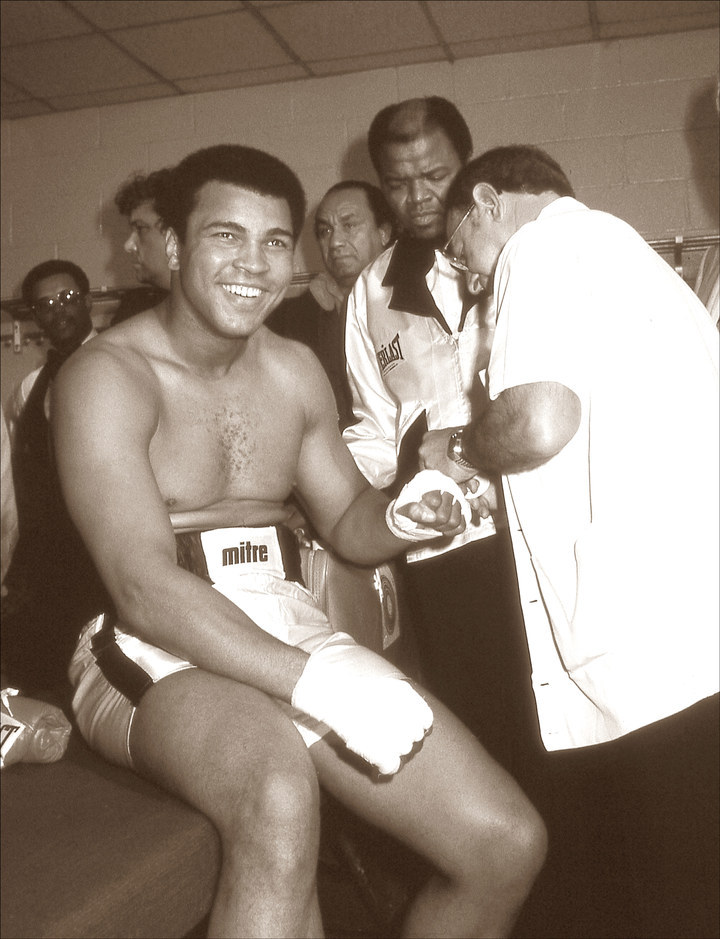 Minutes before the fight, Angelo Dundee tapes Ali's hands in the locker room.