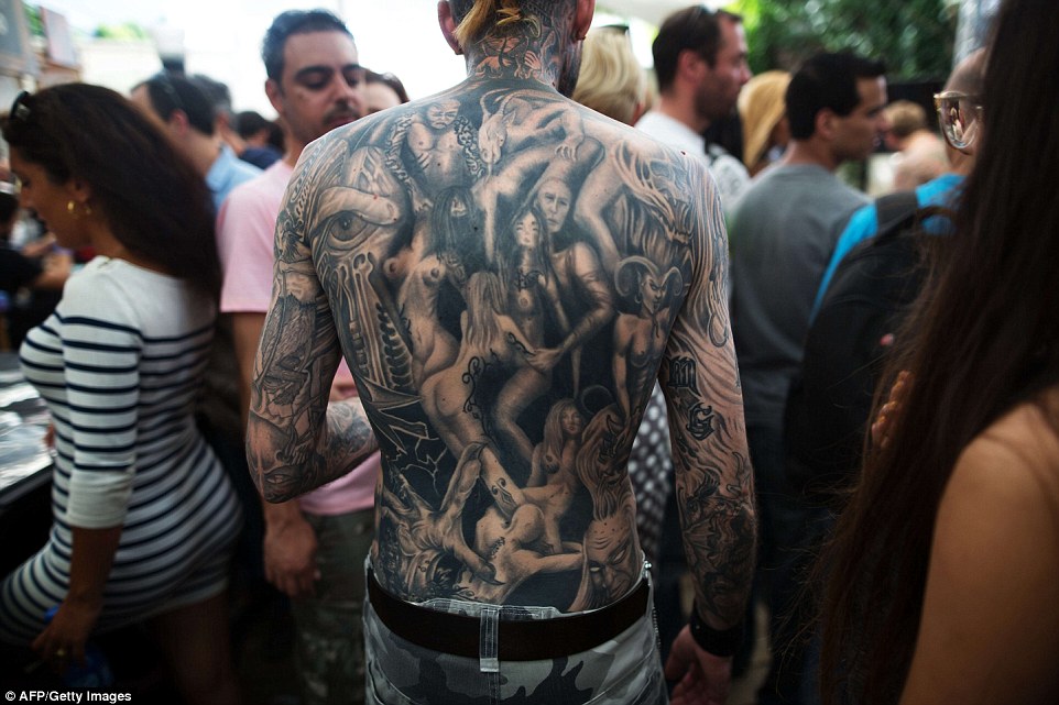 Covered: One man displays his intricate back tattoo at the festival, featuring a series of nude women posing provocatively