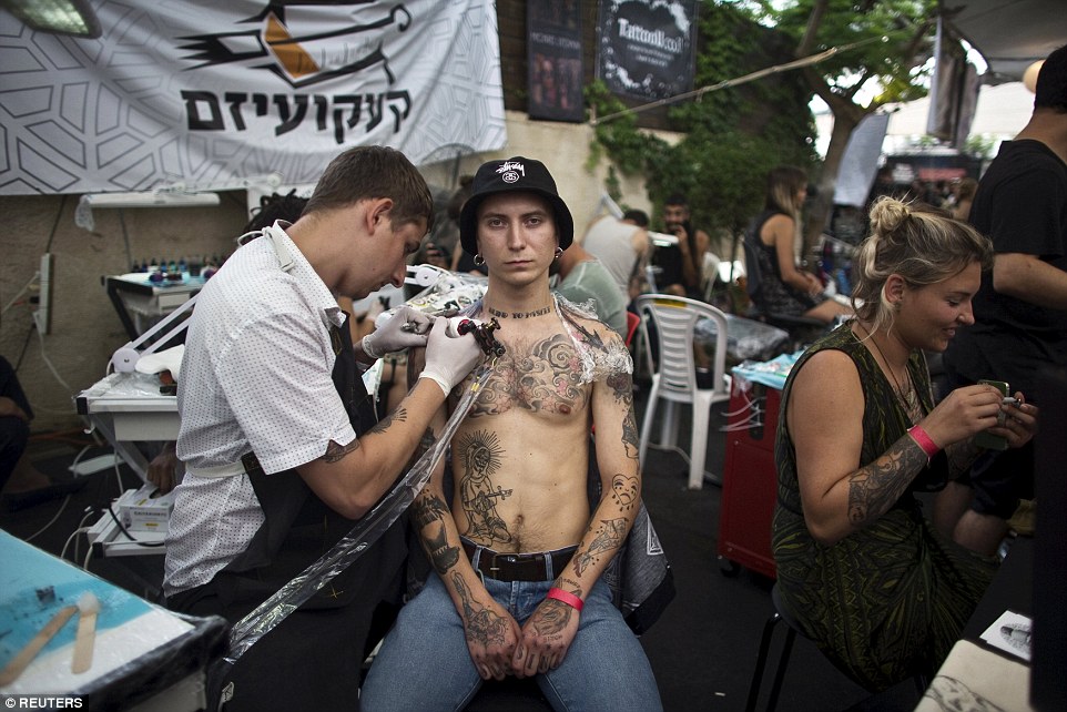 No pain: A heavily tattooed Israeli shows no emotion as a tattoo artist goes to work on his shoulders at the Tel Aviv convention