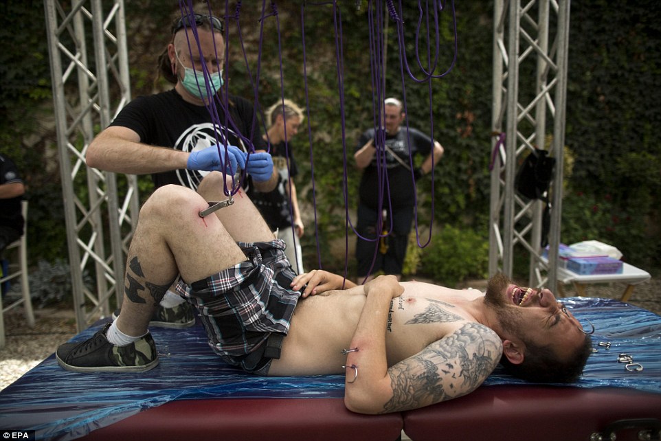 Painful: The 'suspension artist' has mental pins inserted into his thighs before being hoisted up on wires at the Israeli tattoo convention