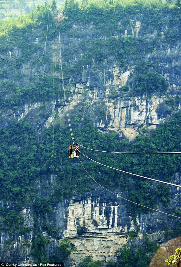 Spine-chilling: Commuters from a remote village in China are forced to use an open cable car to save time when they cross from one side of the cliff to the other