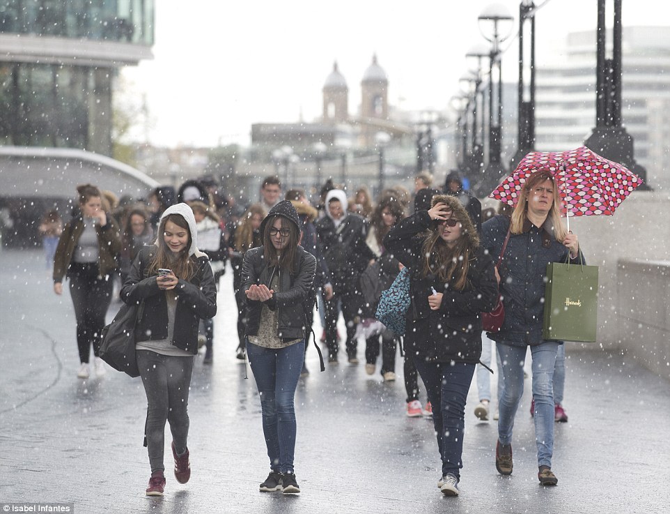 People are caught in a hail storm at the Southbank by Tower Bridge, London, earlier today 