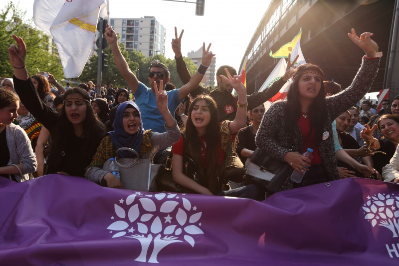 Berlin, Germany. 6th June 2015 -- Female activists shout and show the victory sign. They hold a banner with the logo of the pro Kurdish and left wing HDP. -- About 1,000 march in Berlin Neukoelln and Kreuzberg against recent bombing attacks on the election campaign of pro Kurdish HDP. The participants accuse Turkey's president Recep Tayyip Erdogan for calling his supporters for violence against HDP. Demotix image.