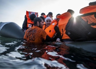A Syrian refugee is helped by a volunteer to leave a sinking dinghy at a beach on the southeastern island of Lesbos, Sunday, Feb. 28, 2016. Greece is mired in a full-blown diplomatic dispute with some EU countries over their border slowdowns and closures. Those border moves have left Greece and the migrants caught between an increasingly fractious Europe, where several countries are reluctant to accept more asylum-seekers, and Turkey, which has appeared unwilling or unable to staunch the torrent of people leaving in barely seaworthy smuggling boats for Greek islands. (AP Photo/Manu Brabo)