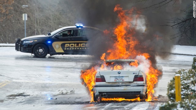 Police monitor a fire in a vehicle left overnight by a motorist who was stranded in Brookhaven, Georgia, on January 29.