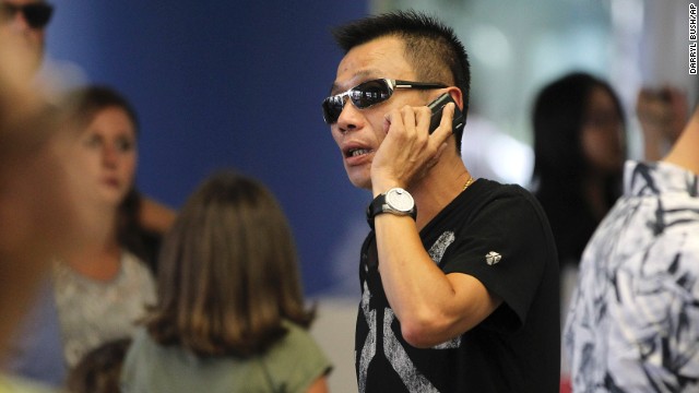 Kevin Cheng talks on his phone as he waits in the terminal after Asiana Airlines Flight 214 crash-landed on July 6. He said he was supposed to pick up students who were on board the flight from Seoul.
