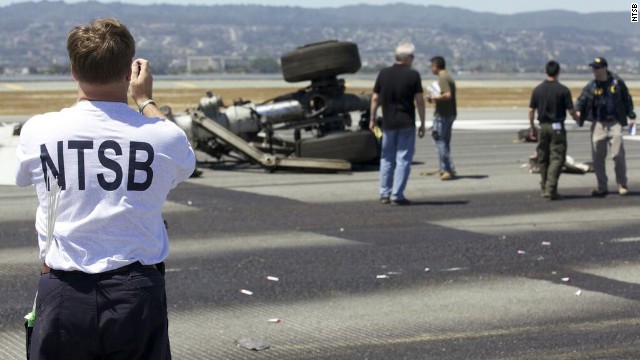 An investigator photographs part of the landing gear at the crash site in a handout released on July 7. Investigators believe that the pilots were flying too slow and too low as they neared the airport on July 6. 