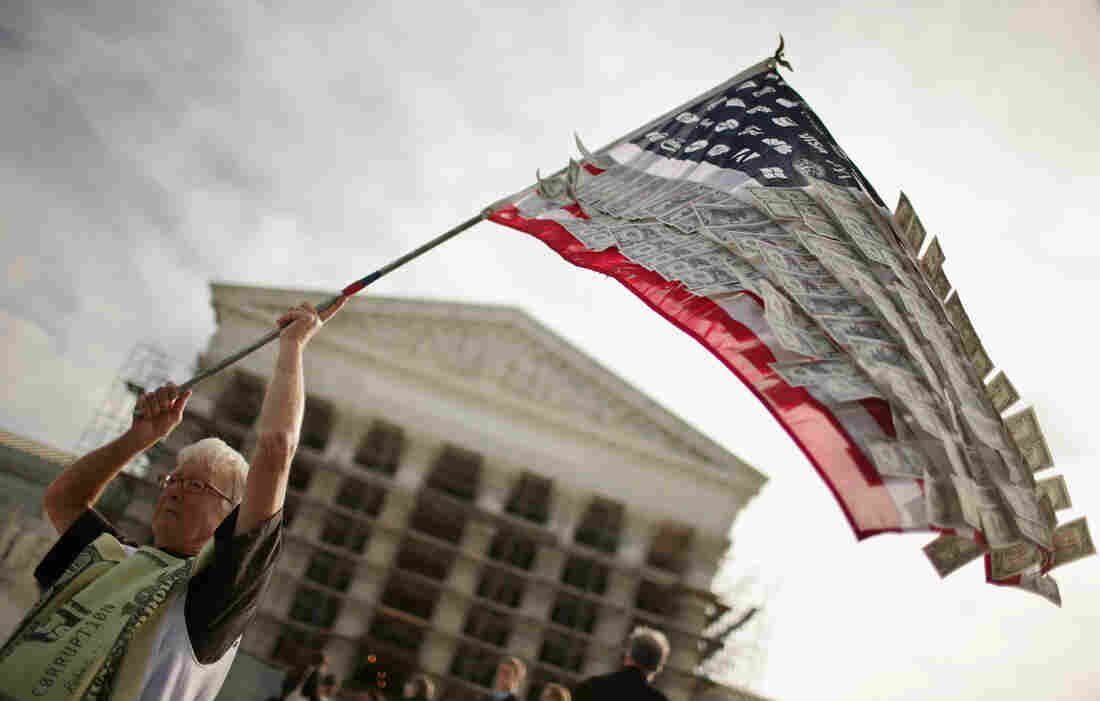 David Barrows, of Washington, D.C., waves a flag with corporate logos and fake money during a rally against money in politics outside the Supreme Court in 2013.