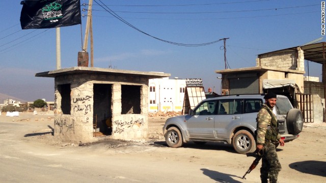 The checkpoint at the entrance to the Syrian town of Addana is where members of the Islamic State in Iraq and Syria, or ISIS, used to dump the bodies of those they had executed to remind others of the consequences of violating their harsh rules. Now that ISIS has left the town, a flag representing the Islamic Front flies over the checkpoint. 