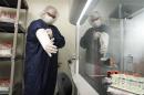 Technician pulls additional sterilized covers on his arms in a Northwest Biotherapeutics laboratory in Memphis