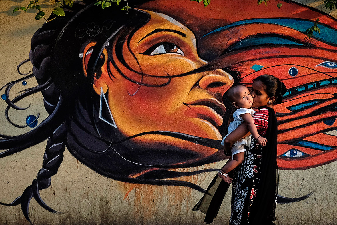 A mother kisses her child as she walks past graffiti in Mumbai