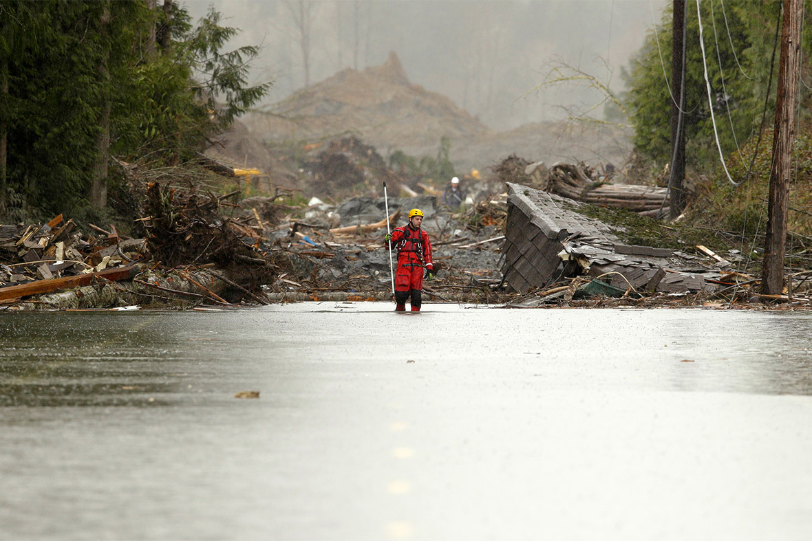 A rescuer stands on a flooded Highway 530 as search work continues in the mud and debris from a massive mudslide that struck Oso near Darrington, Washington State