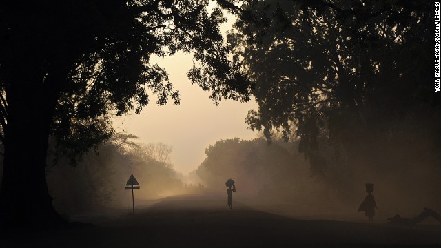 People are silhouetted at dawn on Thursday, February 20, as they walk on the main road to Cueibet, South Sudan. 