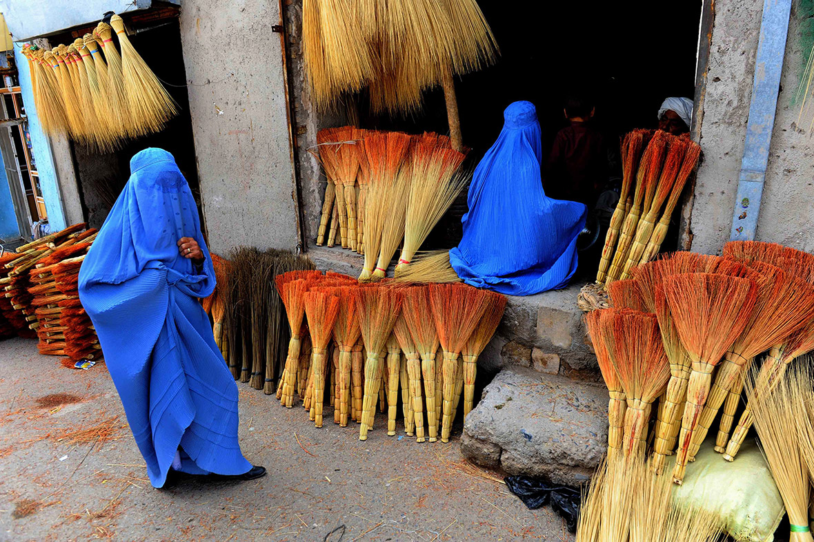 Afghan women look for brooms at a roadside shop in Herat