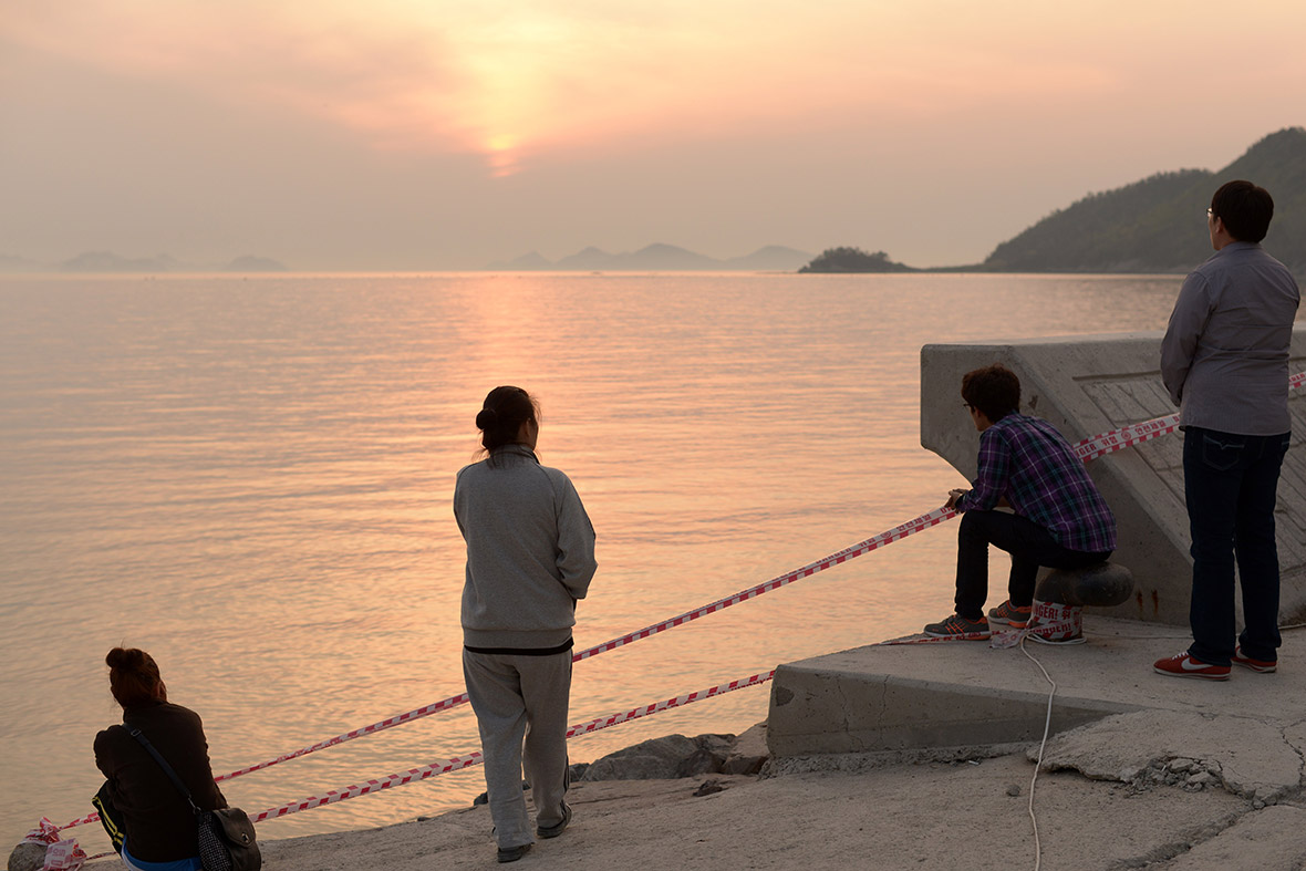 Relatives of missing passengers stare out to sea at Jindo harbour