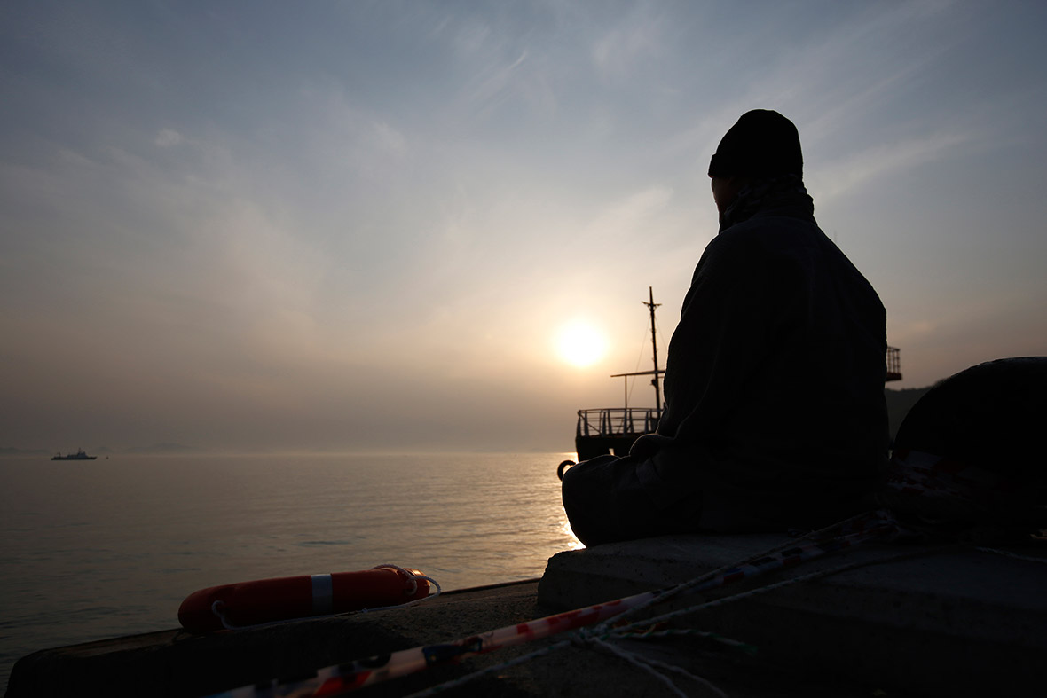 A Buddhist monk faces the sea and prays for the missing passengers