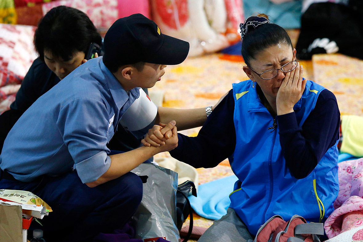 A military medic comforts a woman after she identified her family member on a list of newly found bodies