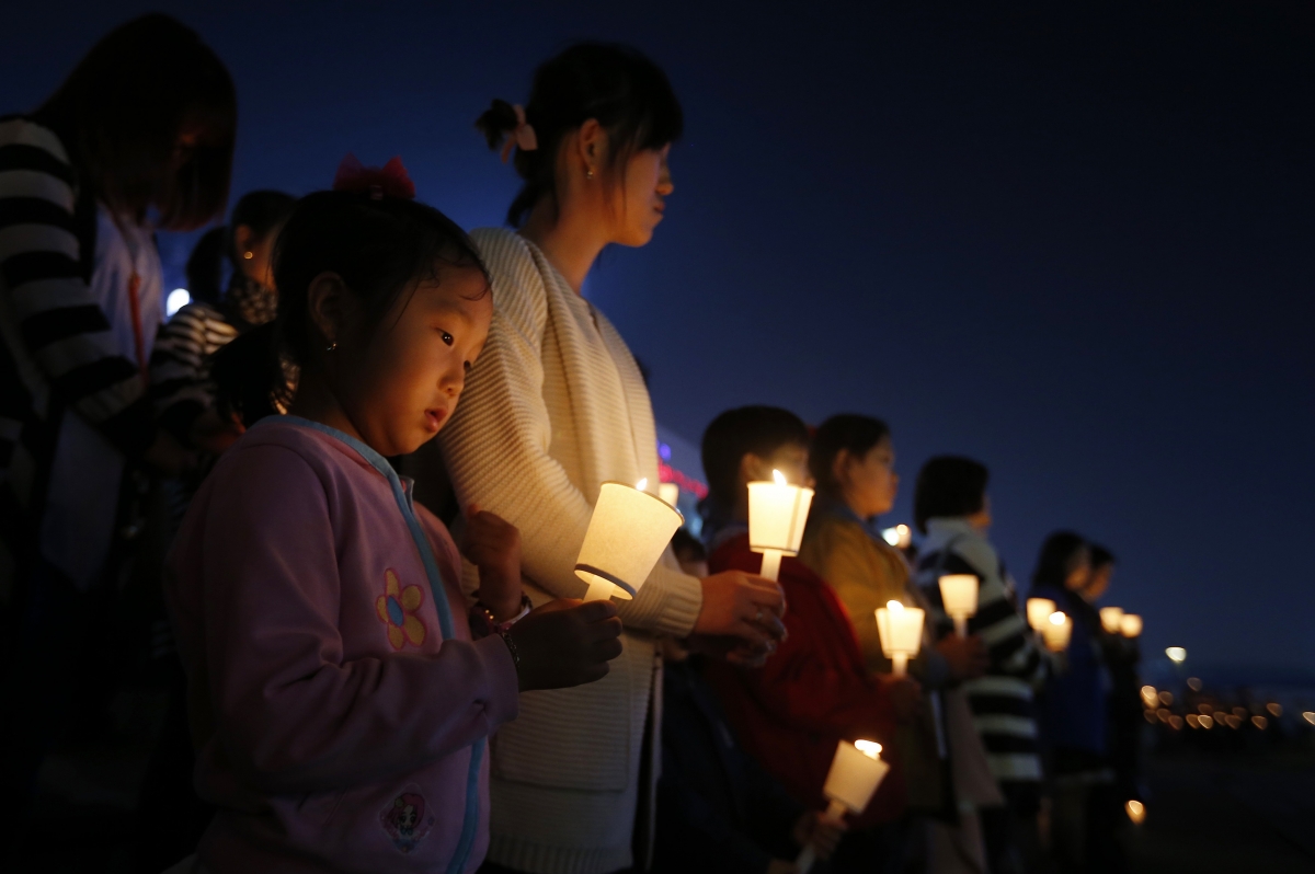 People attend at a candlelight vigil in Ansan, to commemorate the victims of capsized passenger ship Sewol and to wish for the safe return of missing passengers.