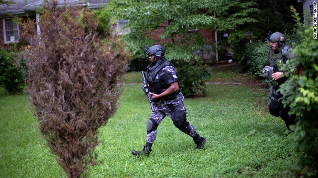 Dekalb County Police SWAT officers run though the front yard of a home toward the elementary school on Tuesday.