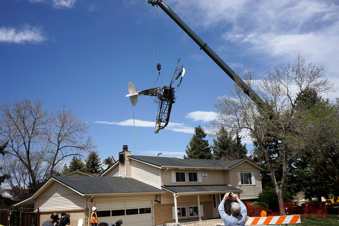 The wreckage of a small plane that crashed into a house is lifted by a crane in Northglenn, Colorado. The pilot of the single-engine plane pulling an advertising banner walked away uninjured after it crashed into an unoccupied home in suburban Denver.